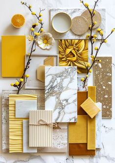 an assortment of yellow and white items on a marble surface with flowers in vases