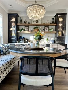 the dining room table is surrounded by black cabinets and white upholstered chairs, with a chandelier hanging from the ceiling