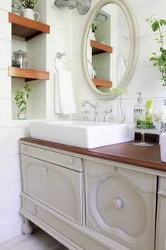 a white sink sitting on top of a wooden counter next to a wall mounted mirror