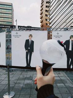 a person holding up a hair dryer in front of two billboards with men's suits on them