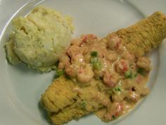 a white plate topped with meat covered in gravy next to mashed potatoes