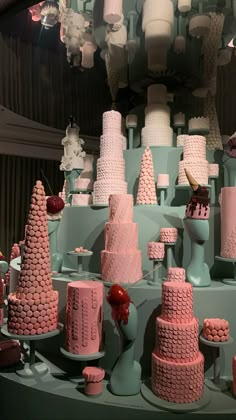 pink and white cakes are on display in a store window, with other decorations behind them