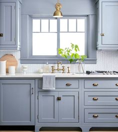 a kitchen with blue cabinets and marble counter tops, an island in the middle is featured on instagram