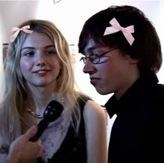 a man and woman standing next to each other with pink bows on their head,