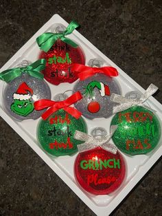 six christmas ornaments with the grinch on them are in a plastic tray and tied together