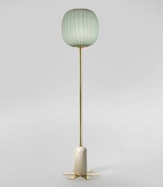 a floor lamp with a light green shade on it's top and gold legs