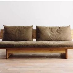 a wooden bench with two brown pillows on it's back and one in the foreground