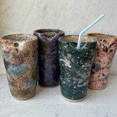 four different colored cups with straws in them