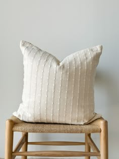 a white pillow sitting on top of a wooden chair