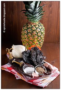 a pineapple sitting on top of a wooden table next to other foods and condiments