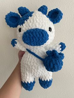 a hand holding a crocheted blue and white stuffed animal that looks like a cow