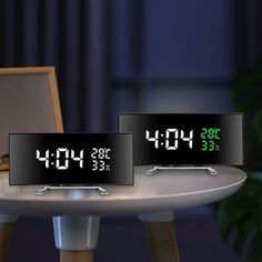 three digital clocks sitting on top of a table in front of a laptop computer screen