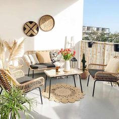 an outdoor living room with wicker furniture and plants on the balcony overlooking the city