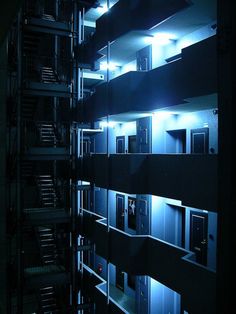 an apartment building is lit up at night with bright lights on the windows and balconies