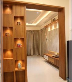 an open door leading to a living room with wooden shelves on the wall and curtains hanging from the ceiling