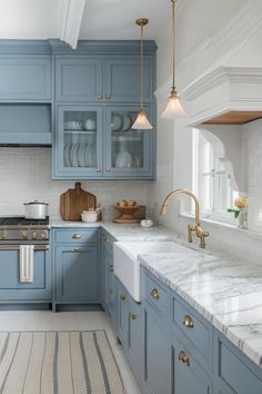 a kitchen with blue cabinets and marble counter tops, gold pulls on the faucet