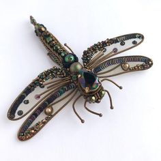 a dragonfly brooch sitting on top of a white table