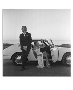 two women and a man sitting on the back of a car