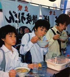 three young men are eating soup at a table