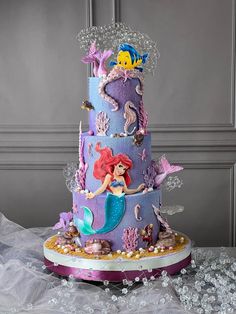 a three tiered cake decorated with mermaids and sea creatures