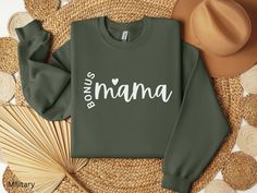 "Show your Bonus Mom or Stepmom how much you care with this Bonus Mama Sweatshirt, its the perfect gift for the incredible stepmom in your life. Whether it's for Mother's Day, her birthday, or just to show your appreciation, this cozy and stylish sweatshirt is sure to put a smile on her face. With its comfortable fit and trendy design, she'll be proud to wear her \"Bonus Mama\" title. Let her embrace her role in style with this Bonus Mama Sweatshirt, because every stepmom deserves recognition for the love and support she brings to the family. UNISEX TSHIRT A classic t-shirt that works well with any outfit, Full of style and comfort *  Made with 100% Airlume combed and ring-spun cotton, a lightweight fabric that is easy to layer, breathable. Perfect for active and leisure wear. * Fabric ble Mom And Bonus Mom Shirts, Bonus Mom Shirt, Relaxed Fit T-shirt With Custom Text For Mother's Day, Mama Shirts Sweatshirts & Hoodies, Mother's Day Screen Print Crew Neck T-shirt, Mother's Day Custom Print Crew Neck T-shirt, Washing And Drying Machine, Bonus Mom Gifts, Mom Sweater