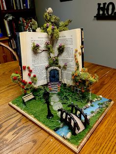 an open book sitting on top of a table covered in fake flowers and plants,