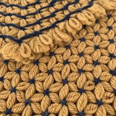 a close up view of a crocheted blanket with blue and brown stripes on it