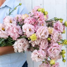 a man holding a bouquet of pink and yellow flowers