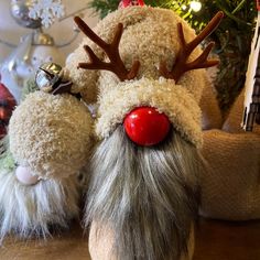 two stuffed reindeers with red noses and antlers on their heads sitting next to a christmas tree