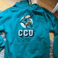 Coastal Carolina Hoodie. Never Worn. Dark Green/Blue Color. Size Small. Blue Collegiate Sweatshirt For Campus, Blue Graphic Print Sweatshirt For Campus, Blue Long Sleeve Hoodie For Team Spirit, Blue Cotton Sweatshirt For Campus, Casual Blue Sweatshirt For Campus, Blue Fleece Hoodie With Team Spirit, Blue Tops For Campus In Fall, Blue Collegiate Fleece Top, Blue Fleece Collegiate Tops