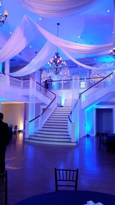 an elegant wedding venue with white drapes and chandelier draped over the staircase