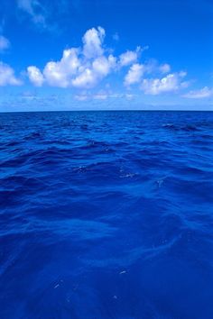 the water is very blue and there are clouds in the sky