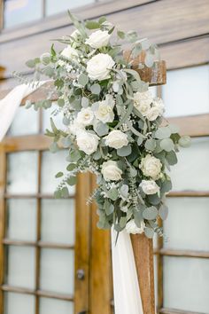 a bouquet of white flowers and greenery on a cross at the end of a wedding ceremony