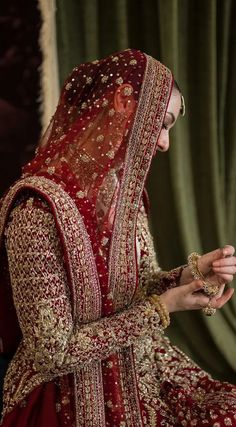 a woman in a red and gold bridal gown is looking down at her wedding ring