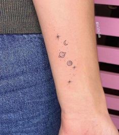 a woman's wrist tattoo with planets and stars on it