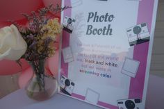 a vase filled with flowers next to a photo booth sign