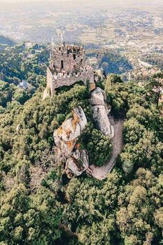 an aerial view of a castle on top of a hill in the middle of trees