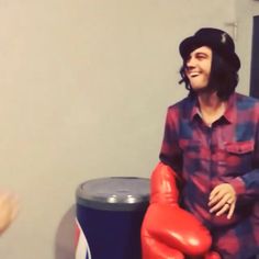 a man with long hair sitting on top of a chair next to a red balloon