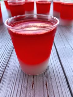 several cups filled with liquid sitting on top of a wooden table