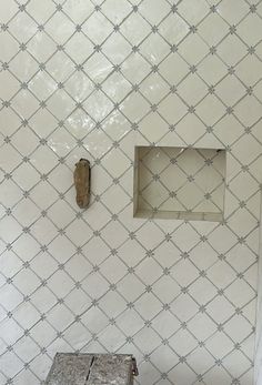 a white tiled bathroom with an old wooden box on the floor and a square window in the wall