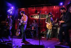 a group of people that are standing in front of some microphones and guitares