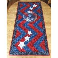 a red, white and blue table runner on a wooden table with a glass bowl