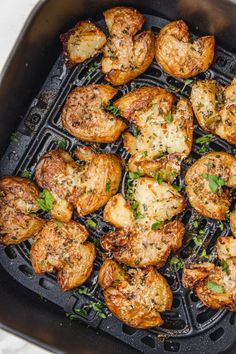 chicken and potatoes cooking in an air fryer with parmesan cheese on top