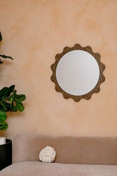 a living room with a couch, mirror and potted plant on the side wall