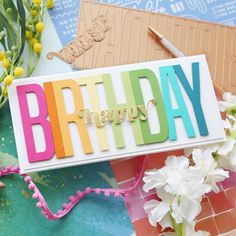 a birthday card sitting on top of a table next to some flowers and other items