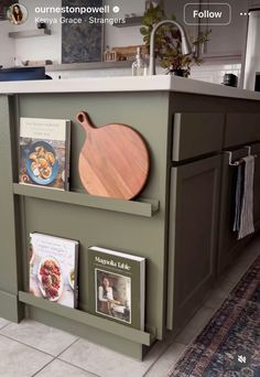 a kitchen with green cabinets and wooden cutting board