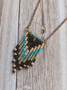 the beaded necklace is hanging from a chain on a wooden table with a white and black background