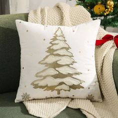 a christmas tree pillow sitting on top of a green couch