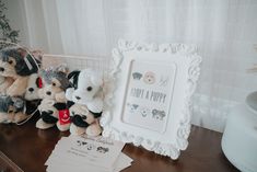 three stuffed animals sitting on top of a wooden table next to a white framed sign