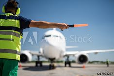 a man in safety gear pointing at an airplane